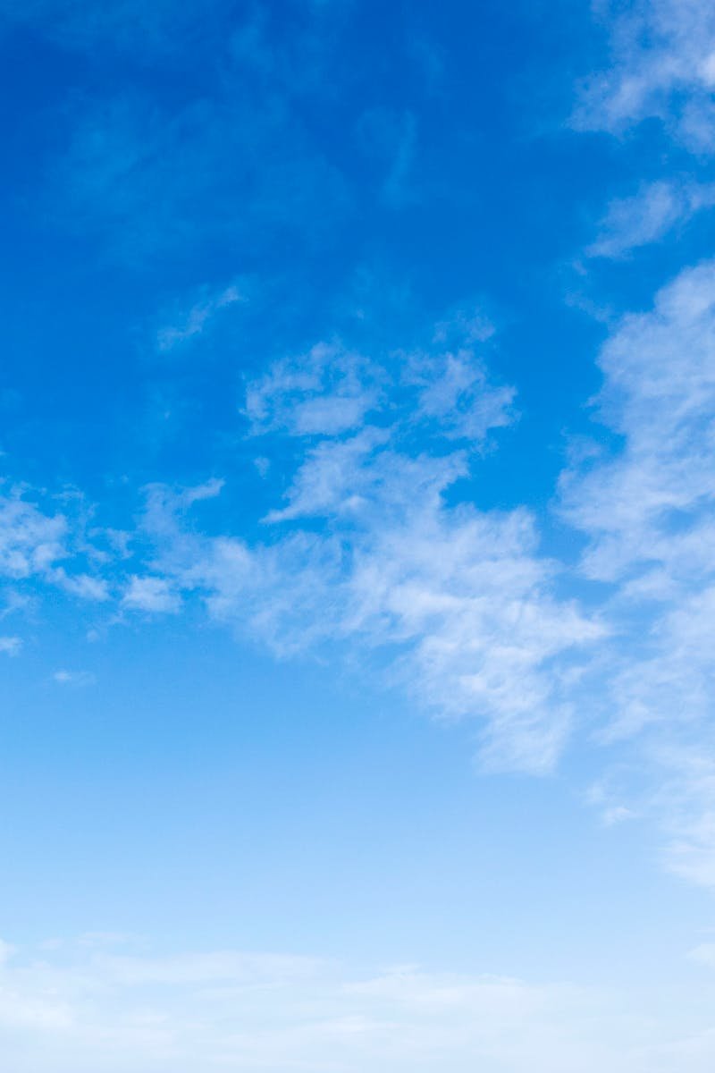 A serene view of a bright blue sky with fluffy white clouds, perfect for backgrounds.